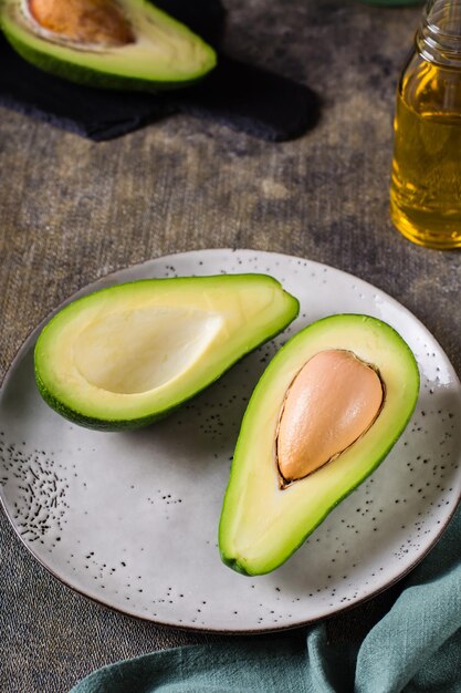 Metades de abacate em um prato sobre a mesa Nutrição vitamínica saudável Visão vertical