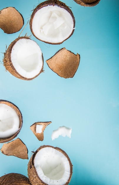 Metades de coco, corte aberto ao meio isolado sobre fundo azul.