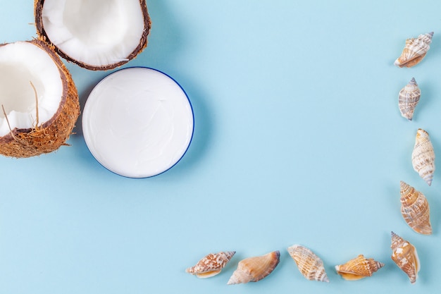 Metades de coco picado sobre fundo azul com conchas e jarra de creme