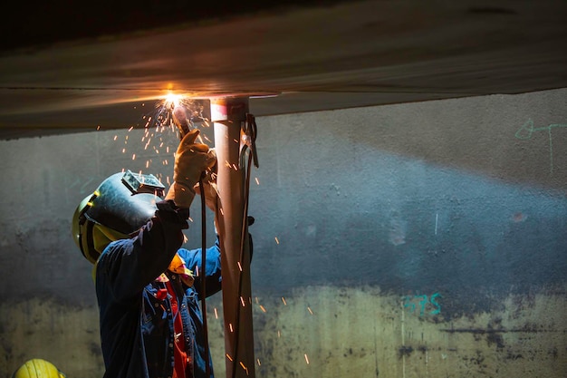 El metal de los trabajadores de soldadura es parte de la construcción de la viga del tanque del techo de la placa de la maquinaria dentro de los espacios confinados