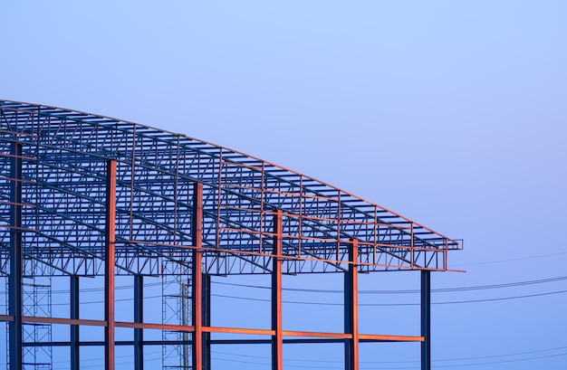 Metall-Industrielagergebäude auf der Baustelle gegen den blauen Abendhimmel bei Sonnenuntergang