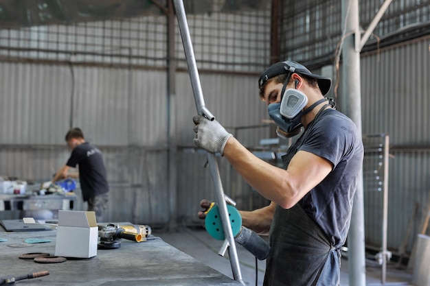 Metallbearbeitungswerkstatt, in der der Meister Metall mit einer Schleifmaschine schleift. Herstellung des Modells