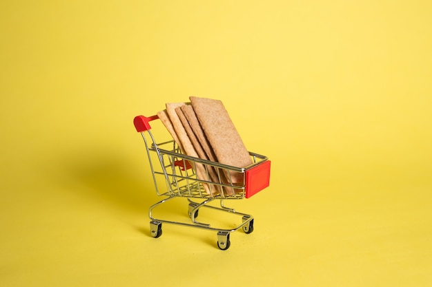 Metallkarren mit Brötchen auf einem gelben isolierten Hintergrund mit Platz für Text