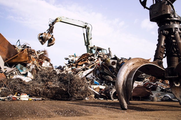 Foto metallschrottplatz mit hydraulischer hebemaschine mit klauenaufsatz für das altmetallrecycling.