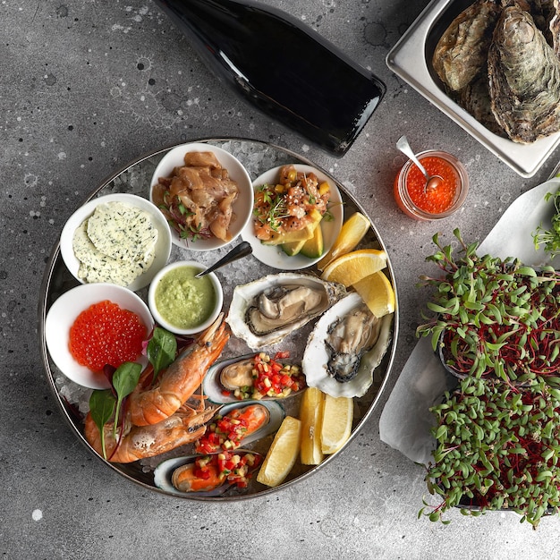 Metalltablett mit offenen Austern, rohen Muscheln und Kaviar Meeresfrüchtesortiment