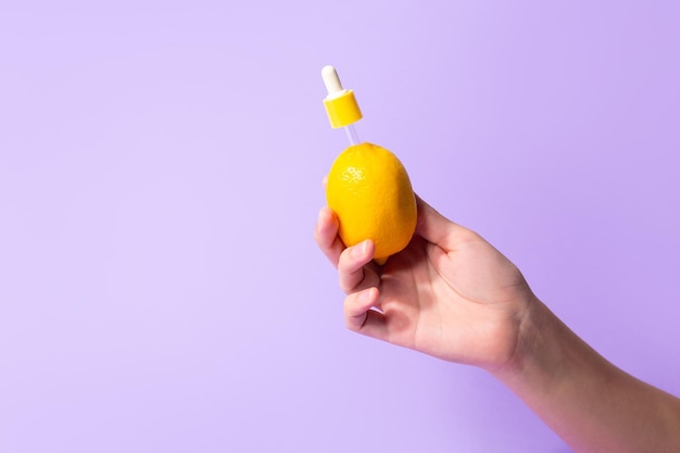 Metapher-Flaschenserum mit Vitamin C für die Haut in der weiblichen Hand der Zitrone Das Konzept der pflanzlichen Kosmetik