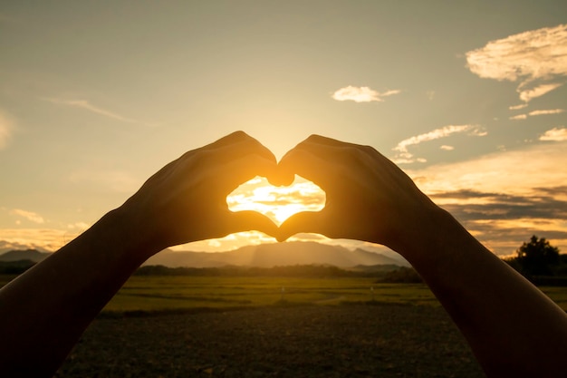 Foto mete a mão no céu ao pôr-do-sol pelo amor