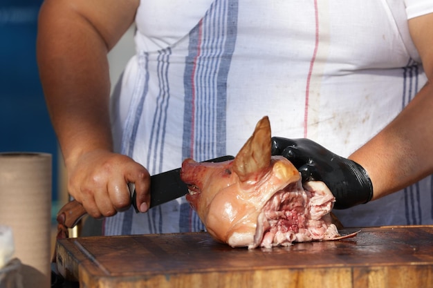 Foto metzger, der ein spanferkelfleisch schneidet