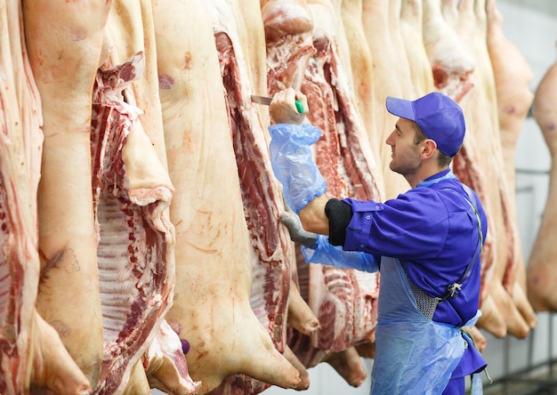 Metzger, der Schweinefleisch bei der Fleischherstellung schneidet.