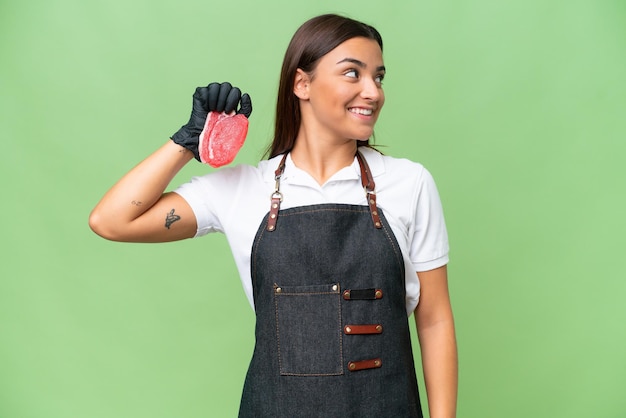 Metzgerin, die eine Schürze trägt und frisch geschnittenes Fleisch serviert, das auf der Seite mit grünem Chroma-Hintergrund isoliert ist