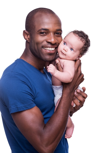 Meu bebê! jovem africano feliz segurando seu bebê e sorrindo enquanto fica isolado no branco