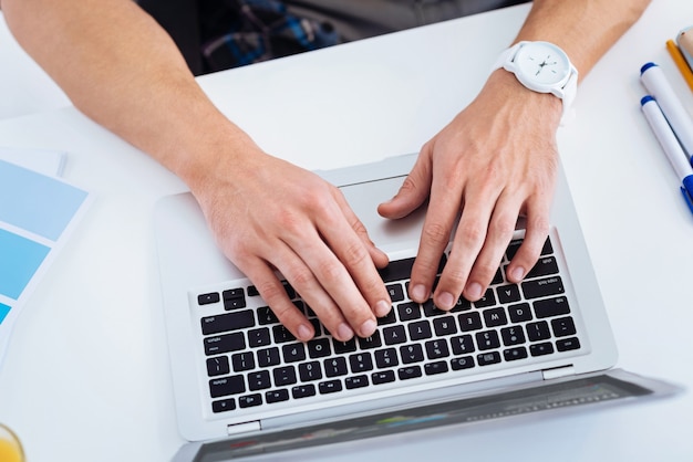 Meu gadget. Jovem trabalhador de escritório sentado em seu local de trabalho e usando o computador enquanto digita e-mail