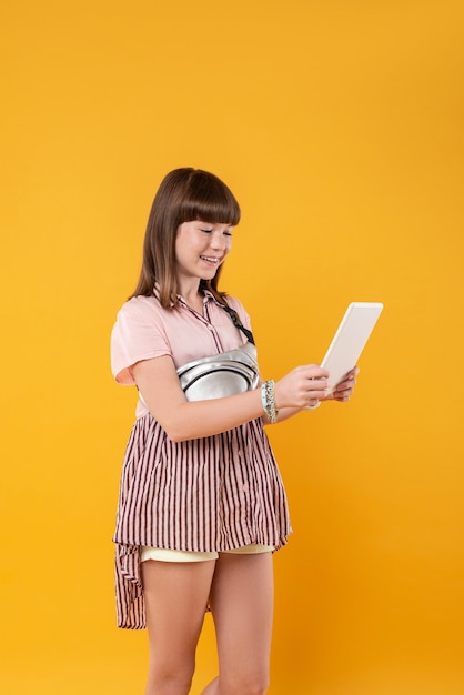 Meu incrível gadget. menina alegre de cabelos escuros sorrindo e segurando seu tablet avançado