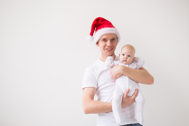 Meu primeiro Natal. Pai com chapéu de Papai Noel segurando sua filha bebê em um fundo branco com espaço de cópia