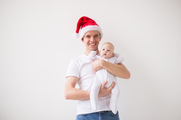 Meu primeiro Natal. Pai com chapéu de Papai Noel segurando sua filha bebê em um fundo branco com espaço de cópia