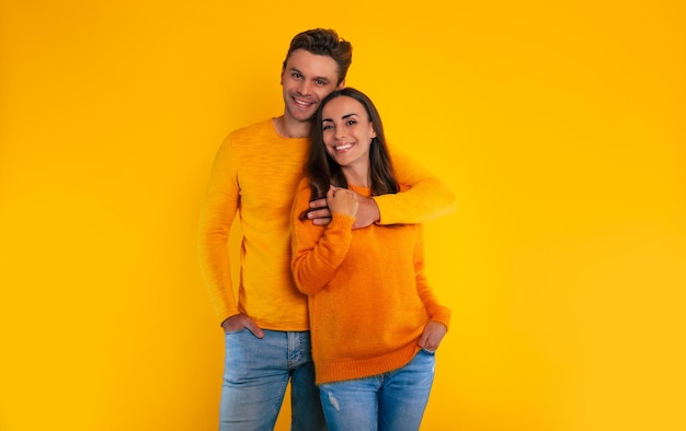 Meu querido! Jovem casal apaixonado e feliz está comemorando o dia dos namorados, abraçando-se e rindo juntos enquanto se isolavam em um fundo amarelo