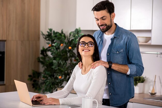 Meu querido marido sorridente massageando os ombros de sua linda esposa na cozinha