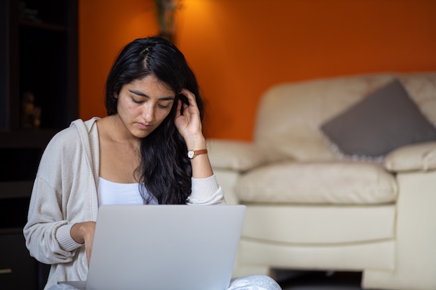 Mexicana mulher sentada na sala de estar com laptop