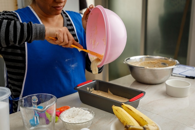 Mexikanerin bereitet einen Bananenpfannkuchen zu und entleert den Teig in den Behälter, um ihn in den Ofen zu legen