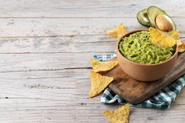 Mexikanische Guacamole mit Nacho-Chip in Holzschale auf rustikalem Holztisch Draufsicht Traditionelles mexikanisches Essen