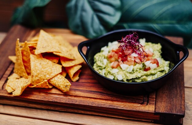 Mexikanische Guacamole mit Nachos-Chips auf Holzbrett