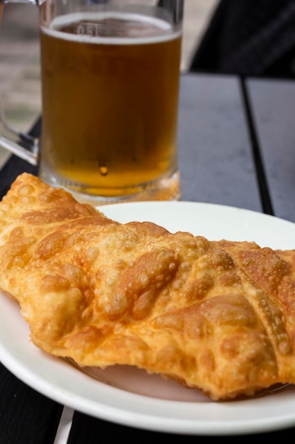 Foto mexikanische maischips nachos, gebratene fleischpasteten empanadas cheburek mit dips und glas bier. schwarze chips-nachos.