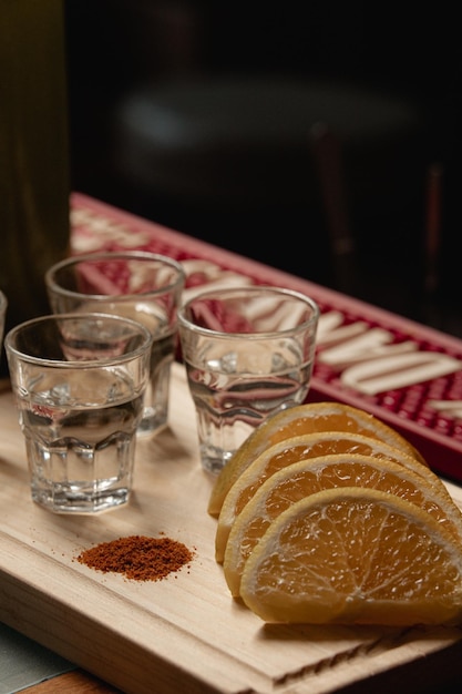 Mexikanische Mezcal-Aufnahmen auf Holzbrett mit Chili und Orangenscheiben