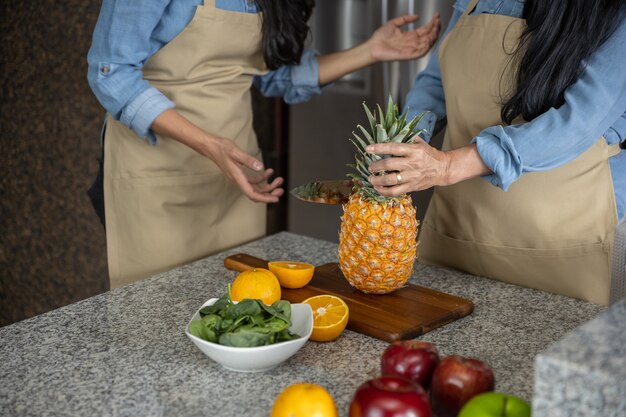 Mexikanische Mutter und Tochter schneiden Früchte in der Küche