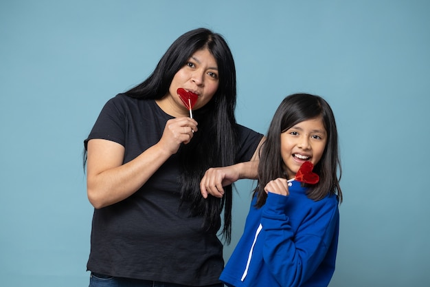 Mexikanische Mutter und Tochter teilen herzförmigen Lutscher