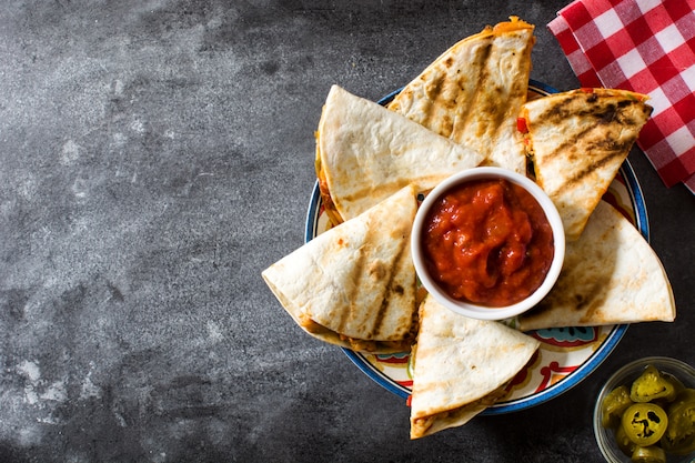 Mexikanische Quesadilla mit Huhn, Käse und Paprika auf schwarzem Hintergrund