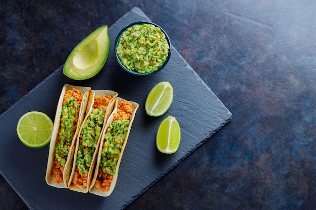 Mexikanische Tacos mit gebratenem Hackfleisch. Tacos mit Hühnchen und Guacamole auf dunklem Hintergrund. Traditionelle mexikanische Küche. Platz kopieren. Ansicht von oben