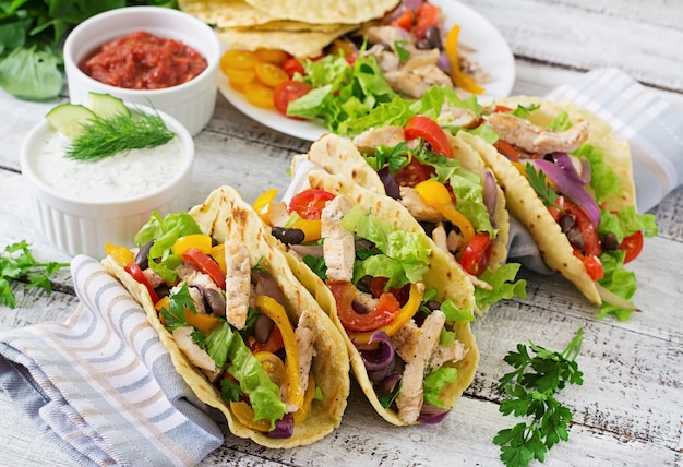 Mexikanische Tacos mit Hühnchen, Paprika, schwarzen Bohnen und frischem Gemüse