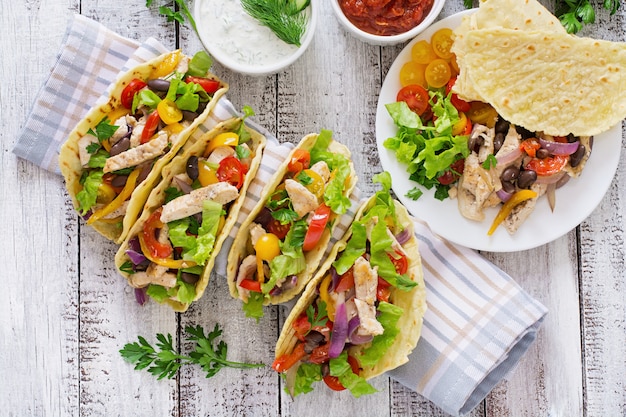 Mexikanische Tacos mit Hühnchen, Paprika, schwarzen Bohnen und frischem Gemüse