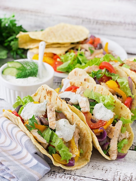 Mexikanische Tacos mit Hühnchen, Paprika, schwarzen Bohnen und frischem Gemüse