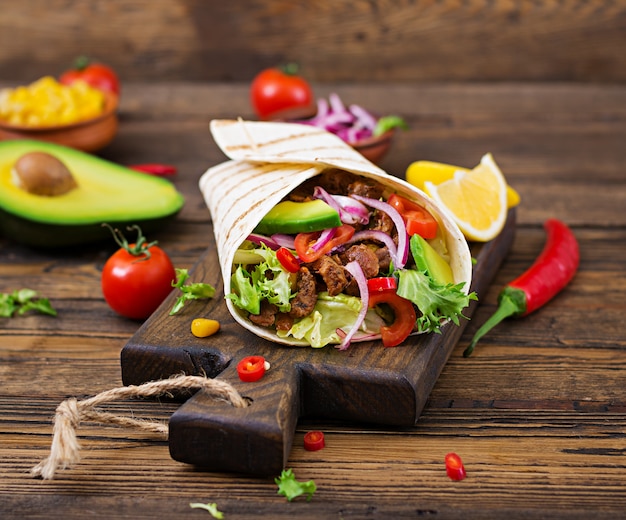 Mexikanische Tacos mit Rindfleisch in Tomatensauce und Avocadosalsa