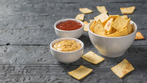 Mexikanische Tortillachips in einer Schüssel mit Sauce und Senf auf dem Tisch.