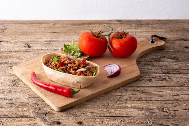 Mexikanischer Barquita Taco mit Rindfleisch, Chili, Tomate, Zwiebel und Gewürzen auf Holztisch