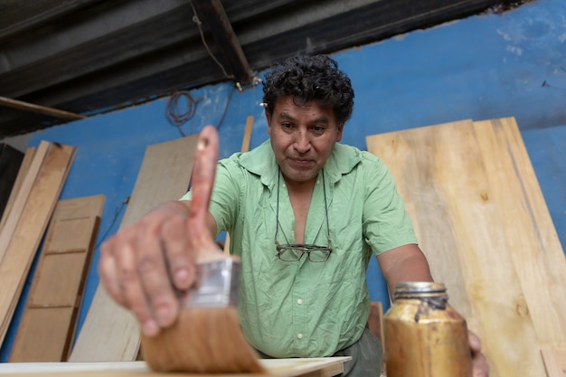 Mexikanischer Holzarbeiter, Tischler beim Lackieren in seiner Werkstatt