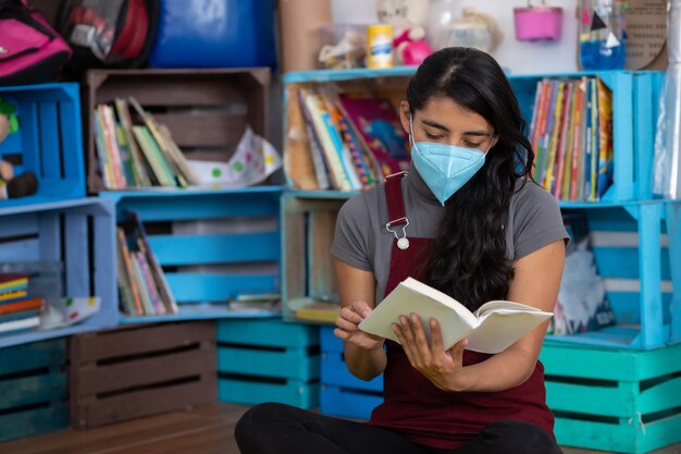 Mexikanischer junger Lehrer, der ein Buch auf einem leeren Klassenzimmer liest