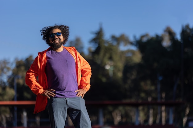 Mexikanischer Latino-Mann mit lockigen Haaren und Bart in einem Park in stolzer Pose