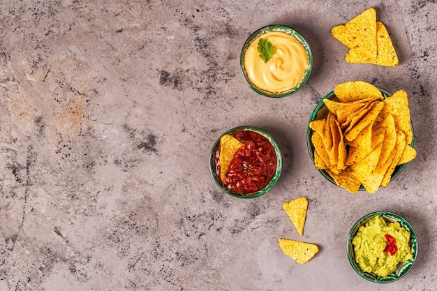 Mexikanischer Lebensmittelhintergrund: Guacamole, Salsa, käsige Soßen mit Nachos, Draufsicht.