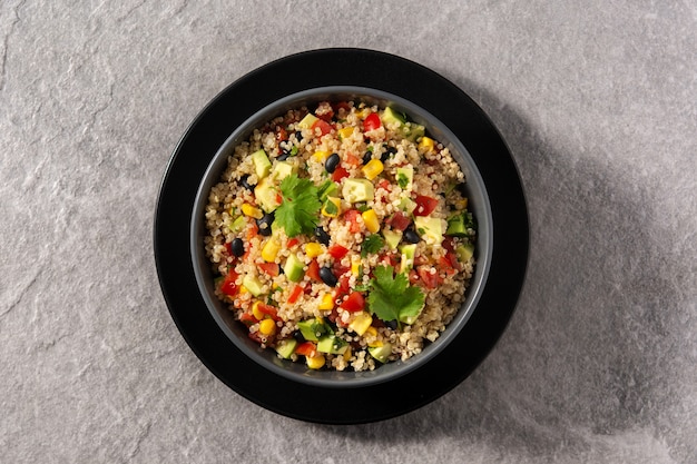 Mexikanischer Salat mit Quinoa in der Schüssel auf Holztisch.