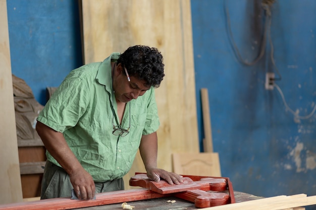 Mexikanischer Tischler beim Schleifen eines Holzkreuzes