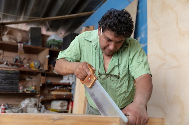 Mexikanischer Tischler, der Holz mit Säge schneidet