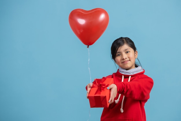 Mexikanisches Mädchen, das ein rotes Geschenk und einen Herzballon liefert, Muttertag