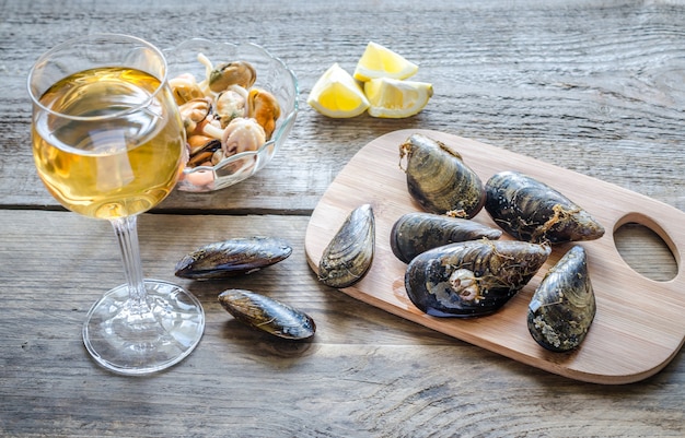 Mexilhões com um copo de vinho branco na mesa de madeira