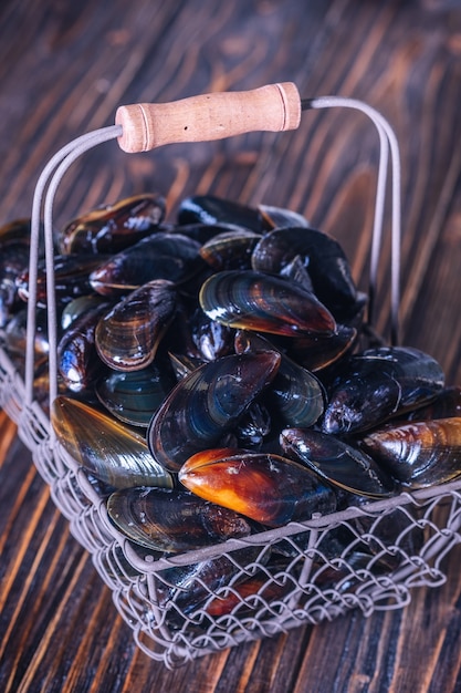 Mexilhões frescos em uma cesta em uma placa de madeira. Frutos do mar.