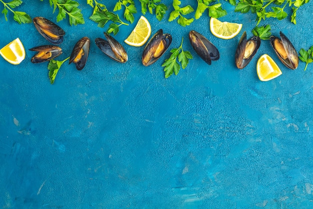 Mexilhões, limão, salsa na superfície de concreto azul escuro