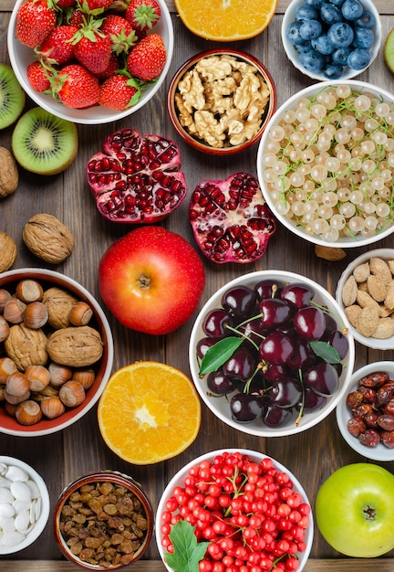 Mezcla de bayas frescas, nueces y frutas sobre fondo de madera