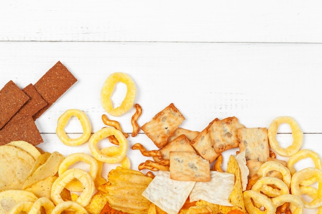 Mezcla de bocadillos: pretzels, galletas, papas fritas y nachos sobre la mesa.
